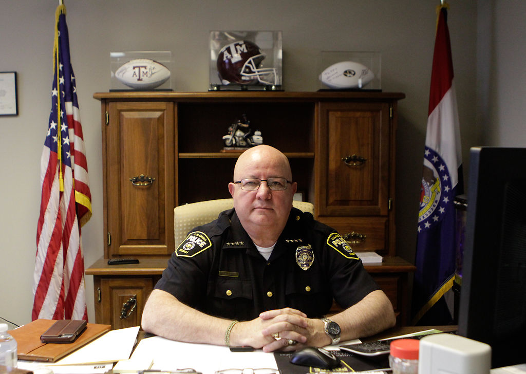 Chief Ken Burton sits at his desk surrounded by work and memorabilia